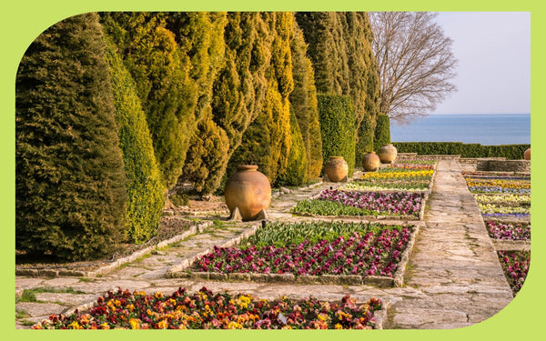 A formal seaside garden with colorful flower beds and an ocean view